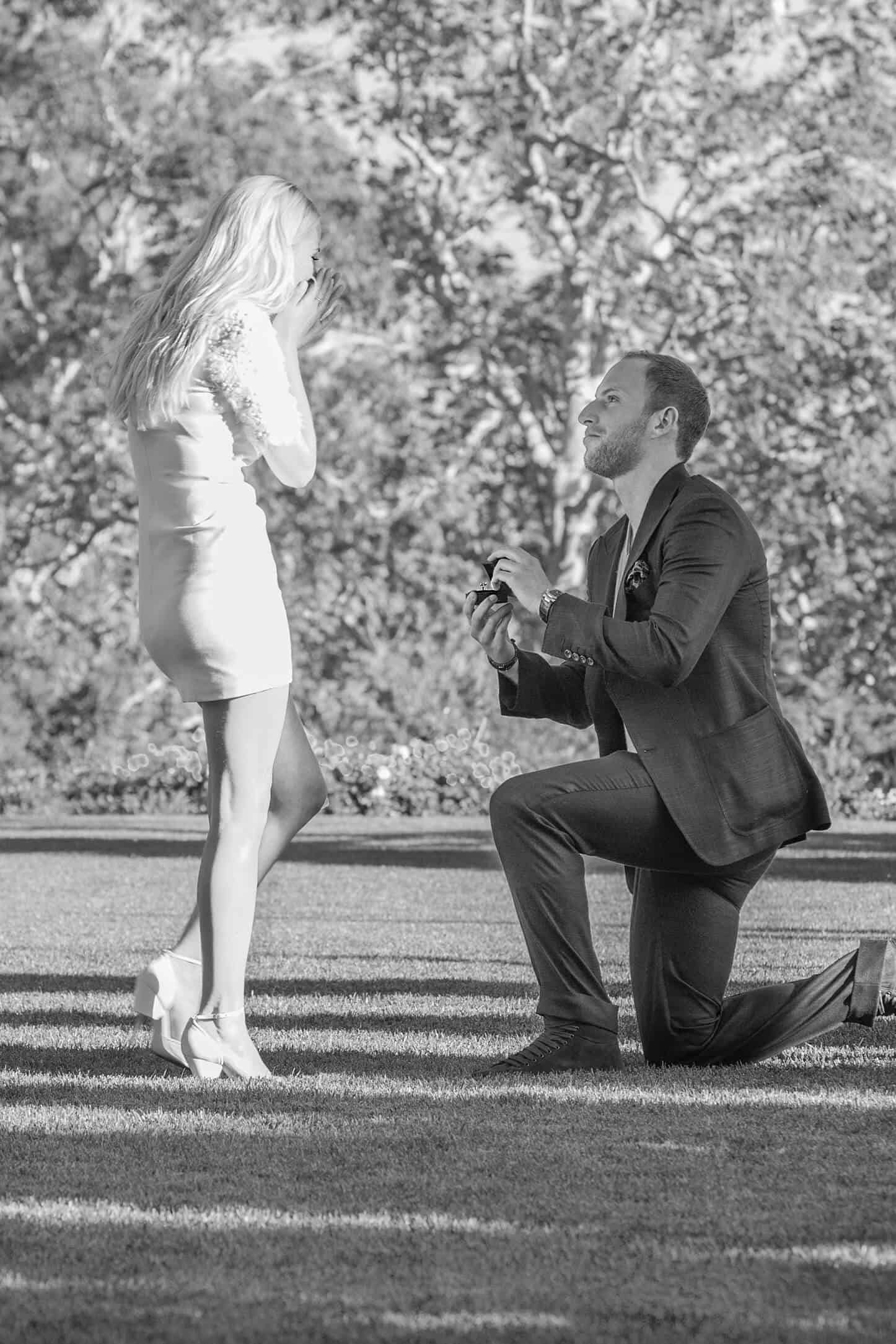 Black & white photo of a couple proposing | for 15 simple proposal ideas blog post