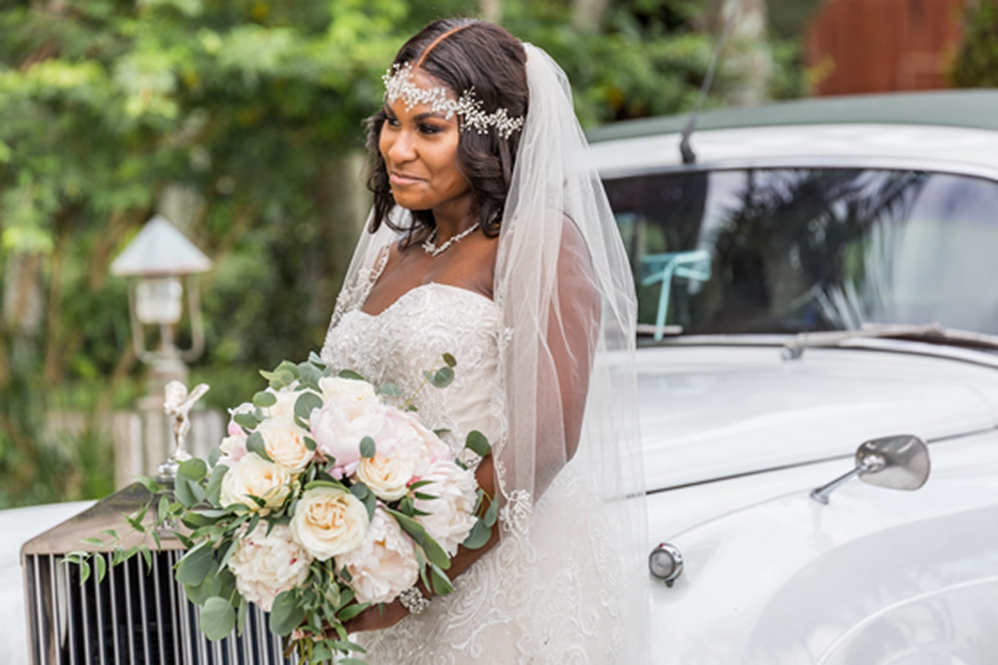 Bride posing beside a vintage Rolls-Royce at the Bamboo Gallery wedding venue in Davie, Florida.